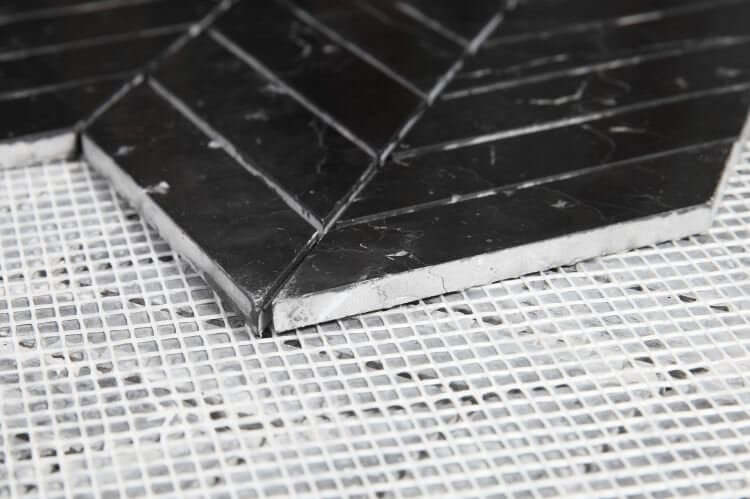 Chevron Marquina marble mosaic tiles in a chevron pattern on mesh backing, polished black finish, ideal for elegant interiors.