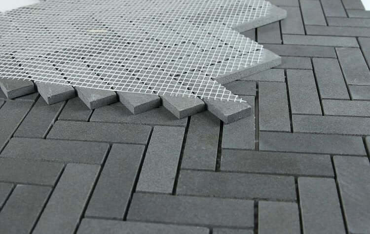 Herringbone Basalt 11x12.5 tile showing dark gray stone pattern with mesh backing for easy installation.
