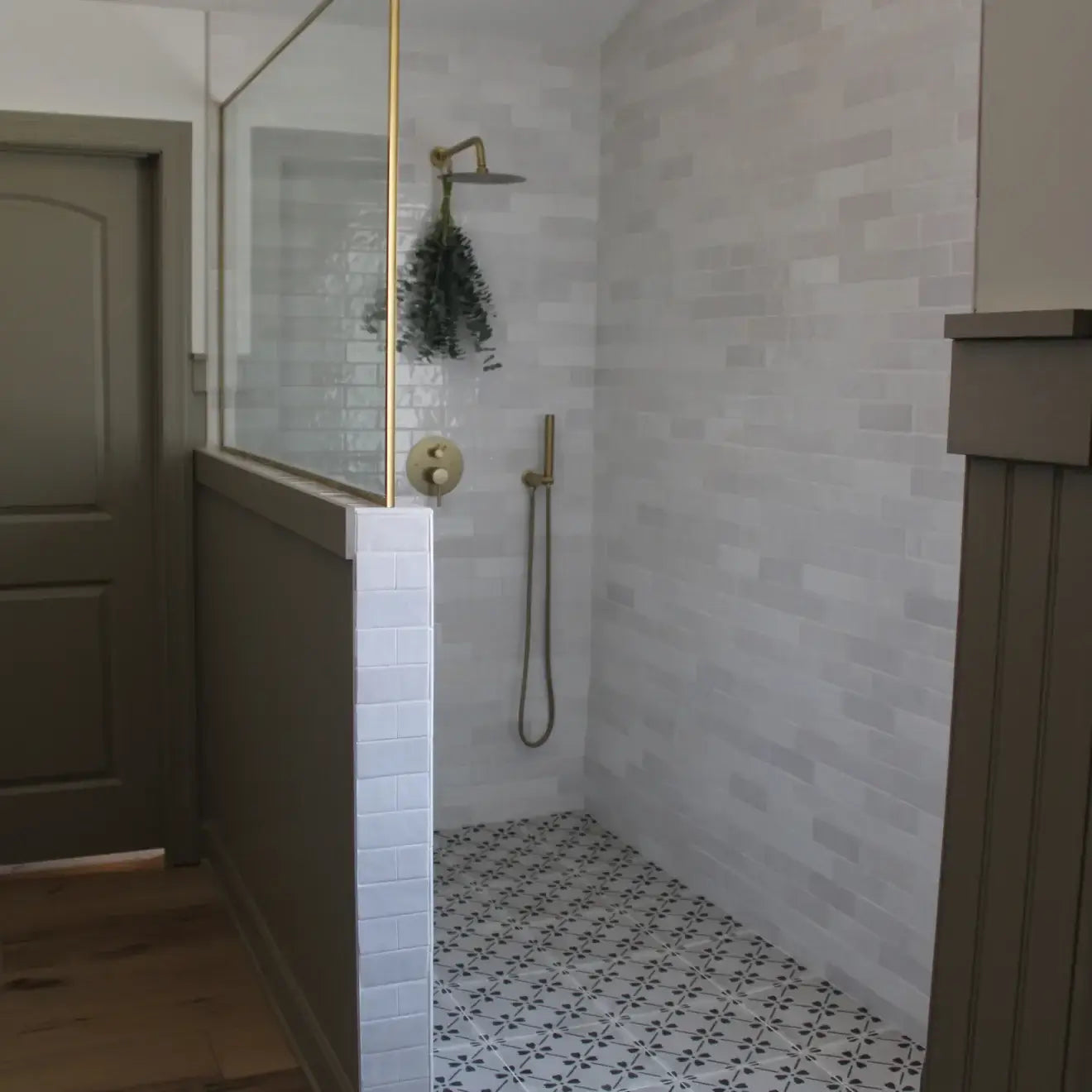 Modern shower featuring white glossy ceramic tile and stylish gold fixtures.