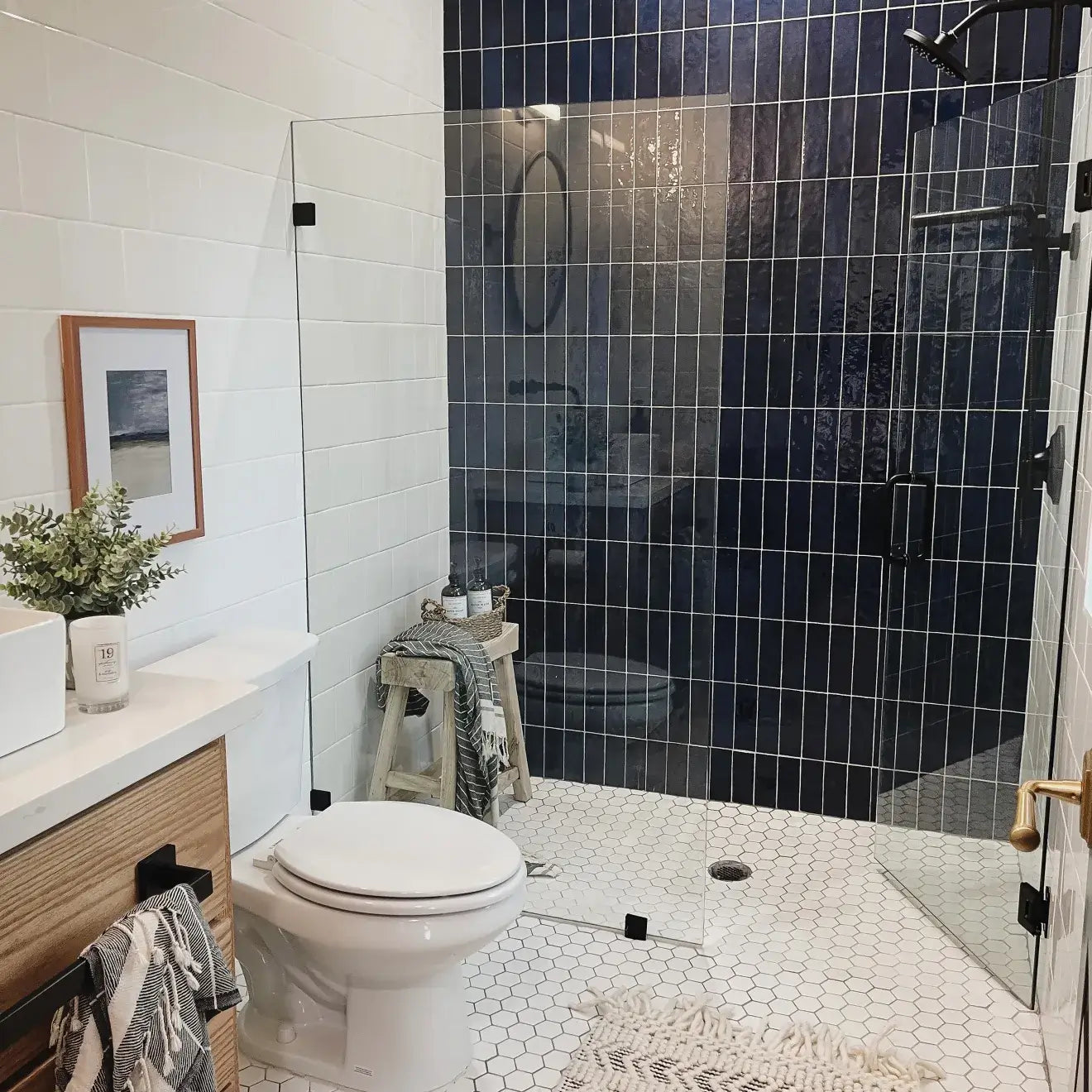 Stylish bathroom with glass shower, glossy blue tile wall, and hexagonal tile floors, showcasing elegant modern design.