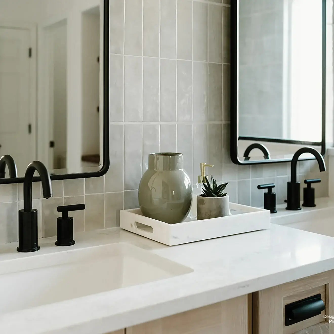 Modern bathroom setup with sleek black fixtures, a marble countertop, and a decorative tray with a vase and succulent.
