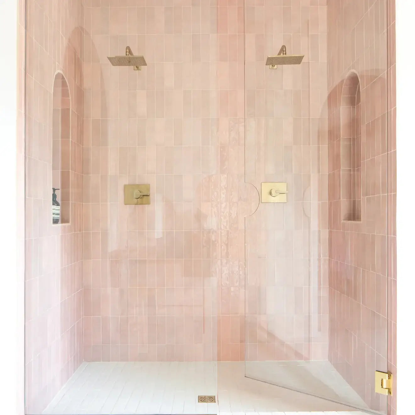 Stylish shower featuring Cloé 2.5" x 8" glossy pink ceramic tile with gold fixtures.