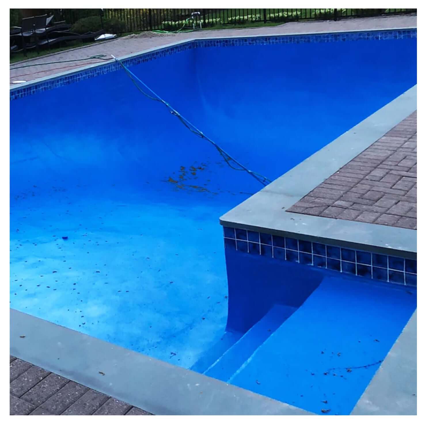 Empty swimming pool with clear blue water and clean stone surrounding, showcasing a modern aquatic design.