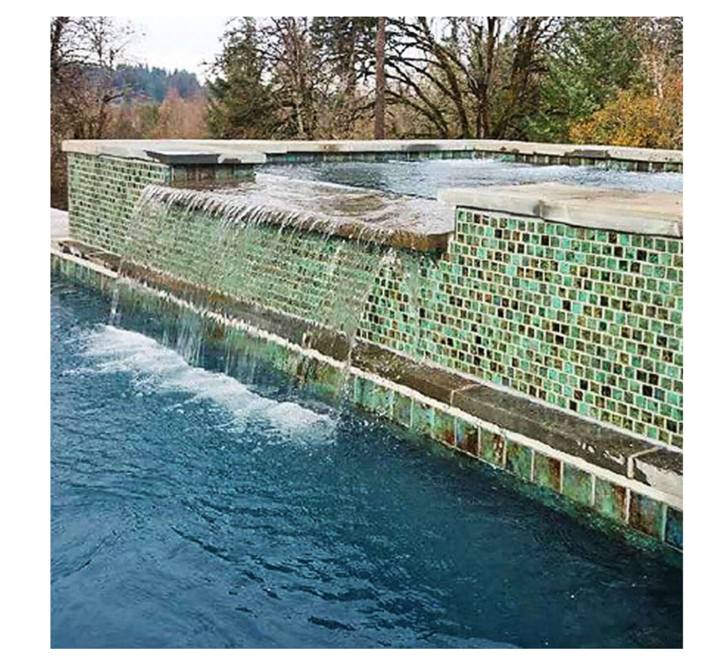 Serene poolscape with green tiles and a cascading waterfall, showcasing vibrant outdoor tranquility.