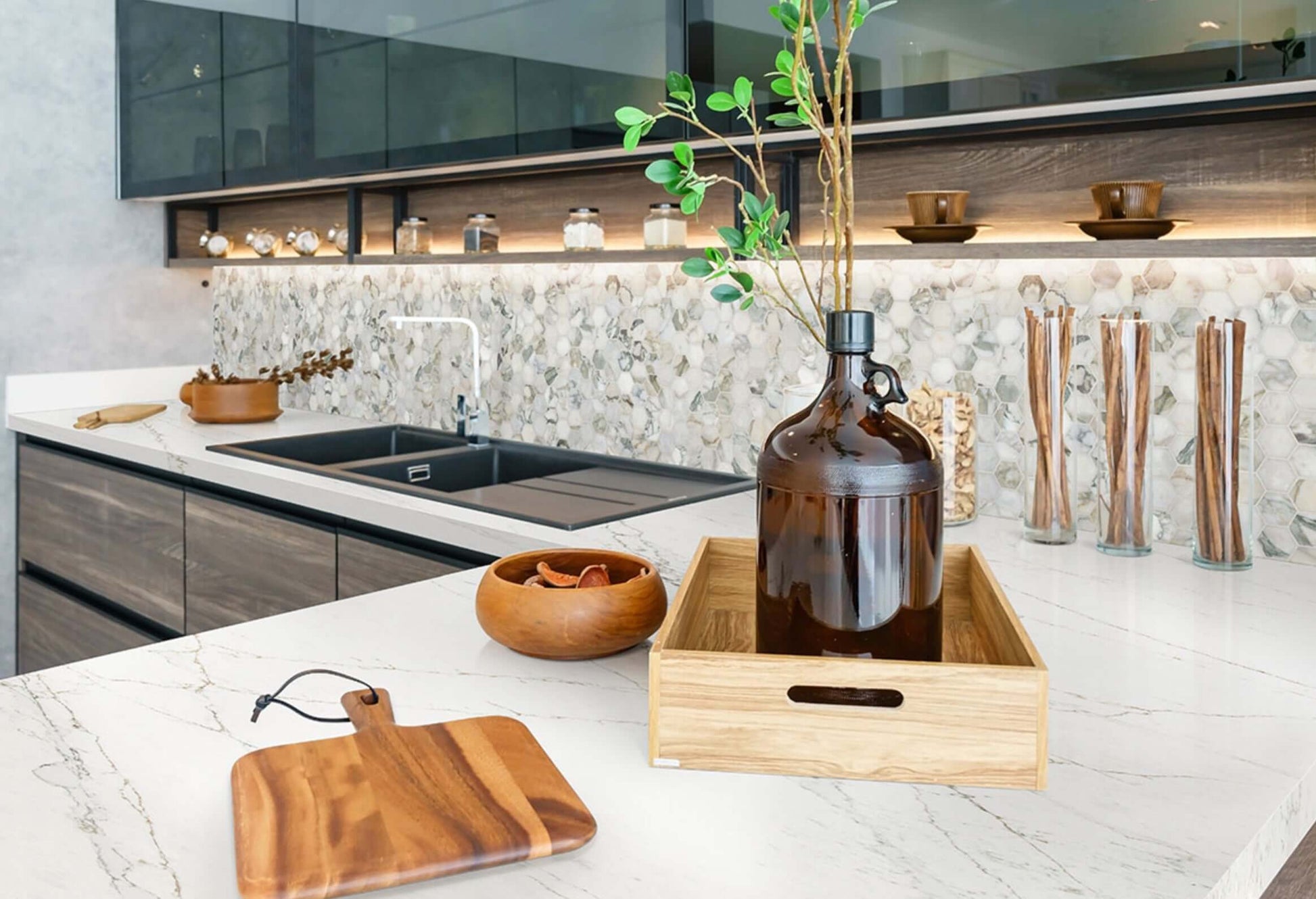 Modern kitchen with marble countertop, elegant decor, and greenery in a glass vase.