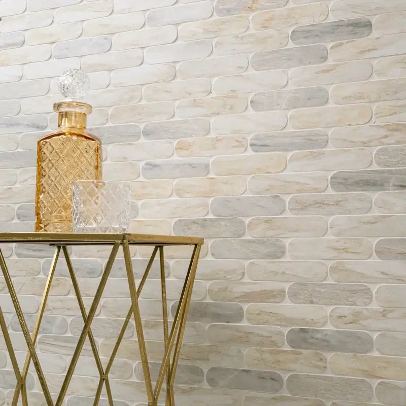 Elegant interior featuring polished marble mosaic wall with golden decor and glassware on a geometric table.