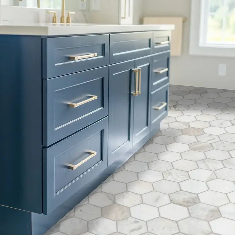 Modern blue kitchen cabinet with gold handles over elegant hexagon marble floor tile.
