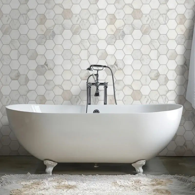 Elegant freestanding bathtub in front of a stylish hexagon mosaic tile wall.