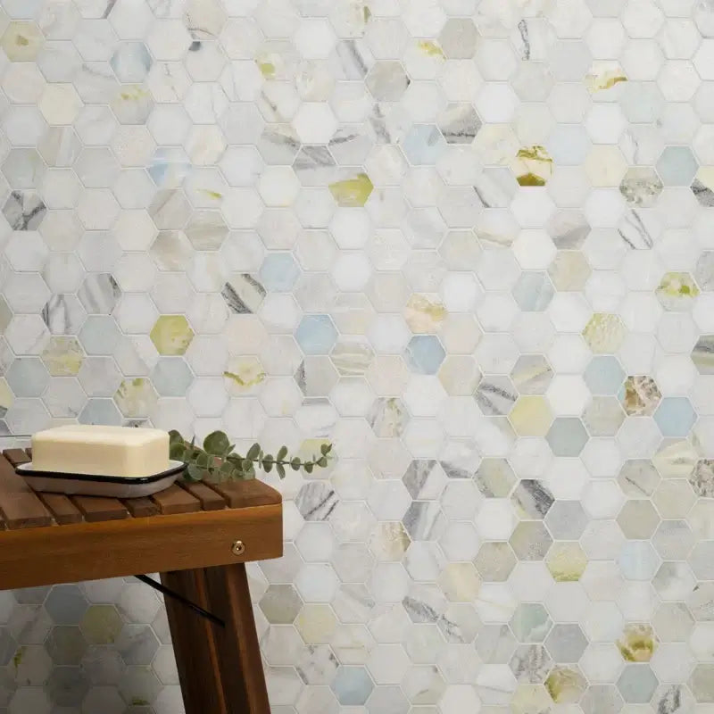 Cloudland 2" hexagon polished marble mosaic tile featuring blue and gray veining on a wall with a wooden table and soap.