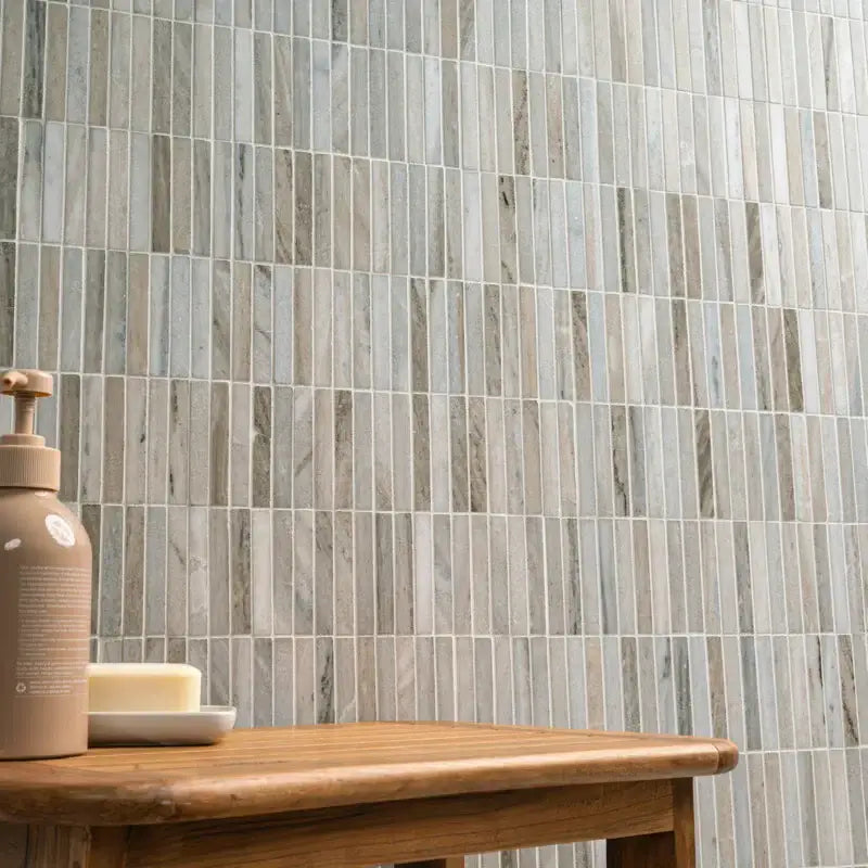 Ravello Mini Stack honed marble mosaic wall tile in contemporary linear design with wooden table and soap.