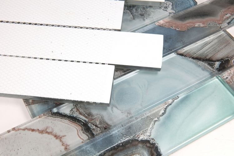 Assorted glass tiles in shades of blue, gray, and white, showcasing elegant patterns for decorative installation.