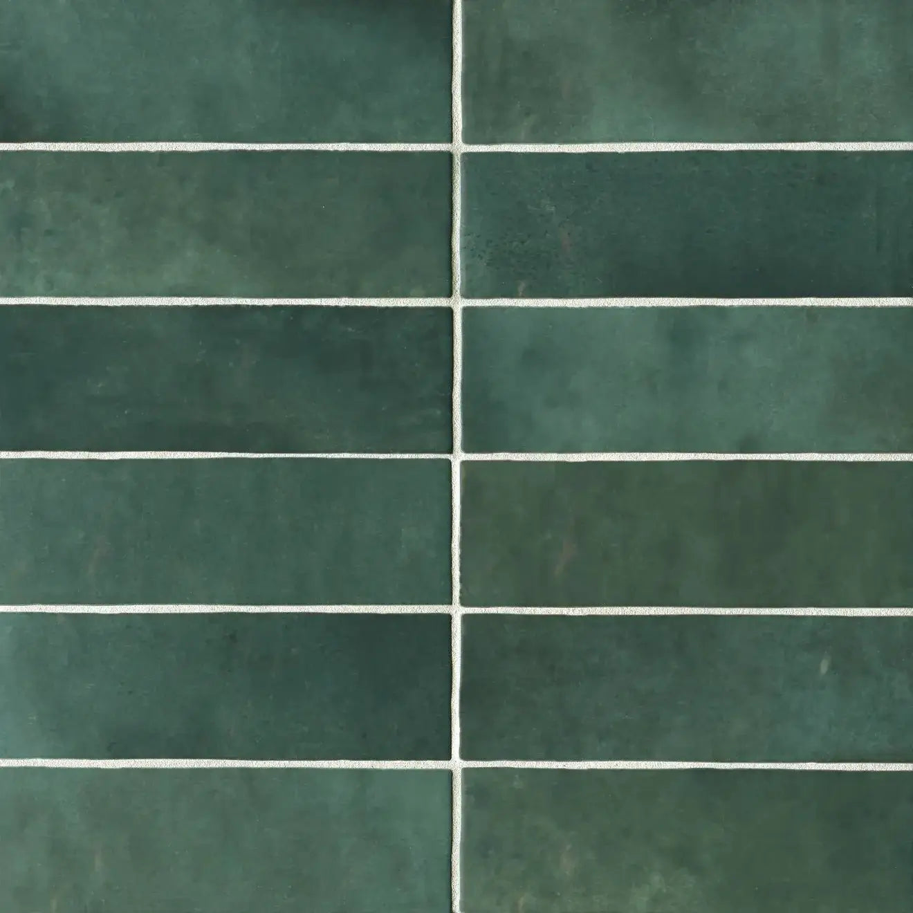 Cloé 2.5" x 8" glossy ceramic subway tiles in rich green with white grout lines.