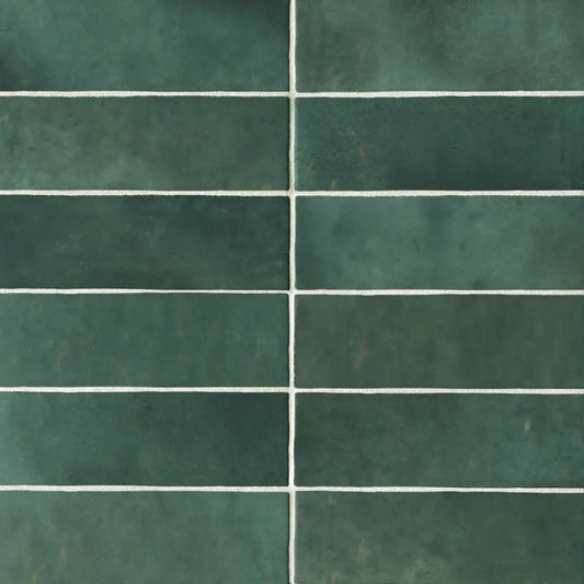 Cloé 2.5" x 8" glossy ceramic subway tiles in rich green with white grout lines.