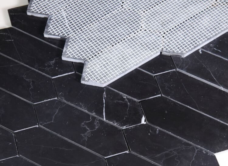 Elongated Hex Marquina marble tiles in black with mesh backing, showcasing honed finish and unique hexagon design.