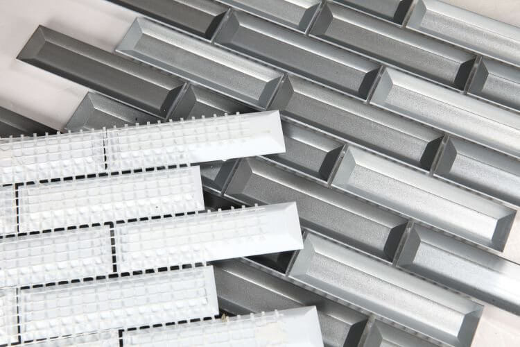 Fierro Cinder 11.75x11.75 glass mosaics in mixed silver and grey, featuring a linear subway pattern.