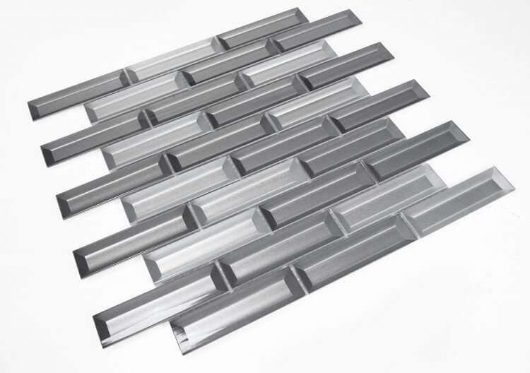 Fierro Cinder 11.75x11.75 glass tiles in a linear subway pattern, featuring silver and grey beveled look.