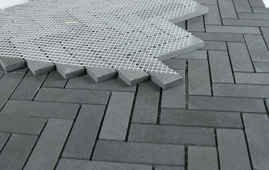 Herringbone Basalt 11x12.5 tile showing dark gray stone pattern with mesh backing for easy installation.