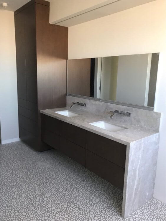 Modern bathroom featuring a sleek double vanity with a stone countertop and pebble mosaic floor.