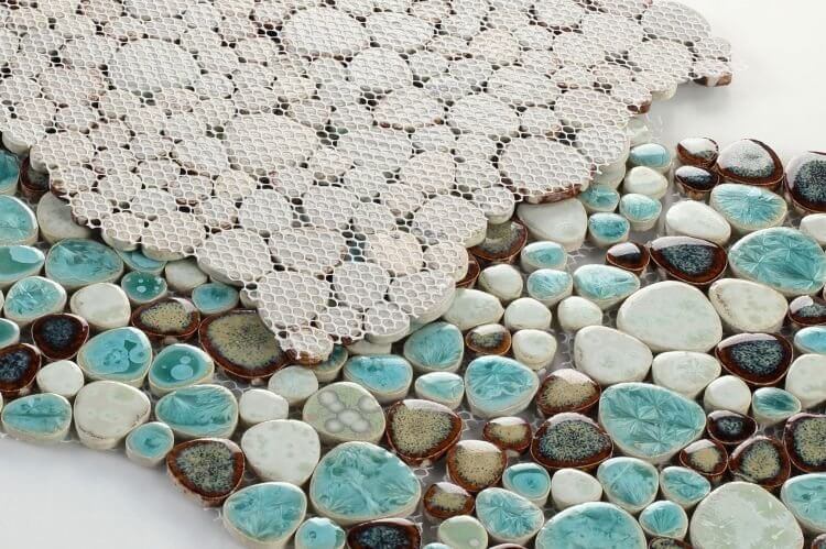 Close-up of turquoise and white pebble mosaic tiles arranged in a mesh sheet, ideal for poolside applications.