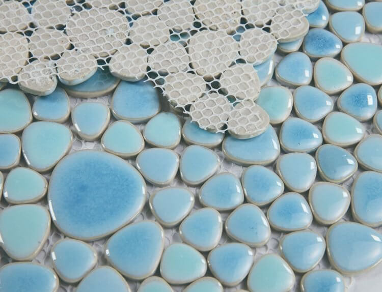 Close-up of light blue pebble mosaic tiles with net backing, perfect for pool and decorative designs.