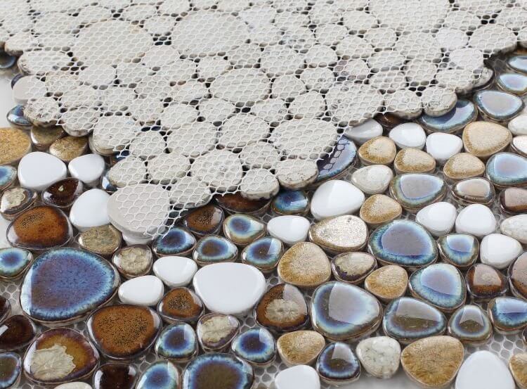 Close-up of Poseidon Mango 11.50 x 11.50 pebble mosaic tile showcasing smooth porcelain pebbles in brown, white, and blue hues.
