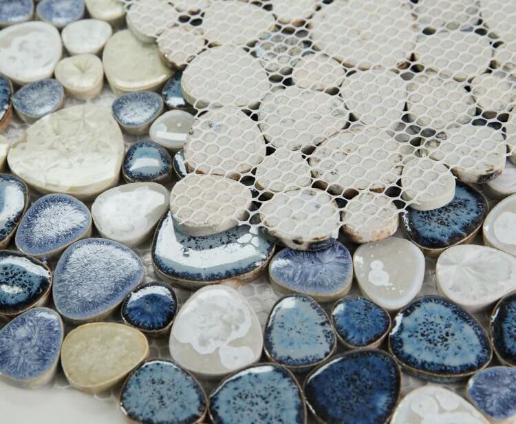 Close-up of Poseidon Ocean 11.50" x 11.50" pebble mosaic tile showcasing smooth blue, white, and beige porcelain pebbles.