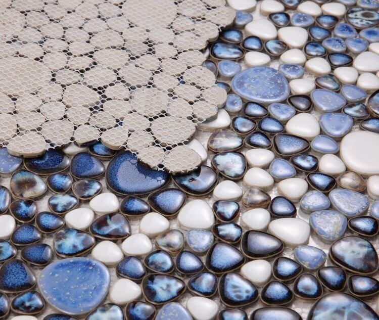 Close-up of Poseidon Royal Blue pebble mosaic tile showing blue and white porcelain pebbles on a mesh backing.