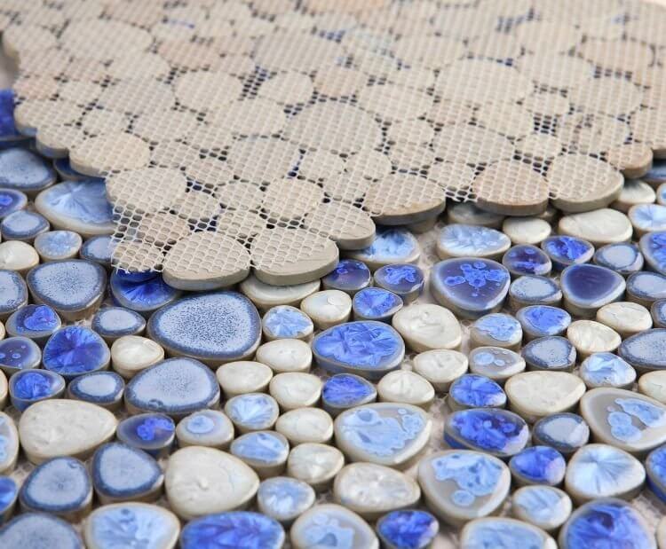 Close-up of Poseidon Sapphire pebble mosaic tile featuring blue and beige porcelain pebbles on a mesh backing.